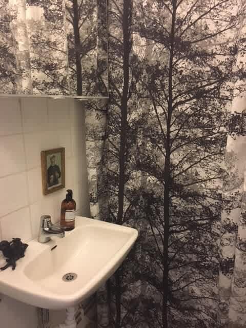Ljust vardagsrum med soffa och konst i lägenhet på Södermalm; Stort sovrum med dubbelsäng på Södermalm; Enkelt sovrum på Södermalm; Ytterligare enkelt sovrum på Södermalm; Utrustat kök med spis och kyl på Södermalm; Privat terrass på lugn gata i Södermalm