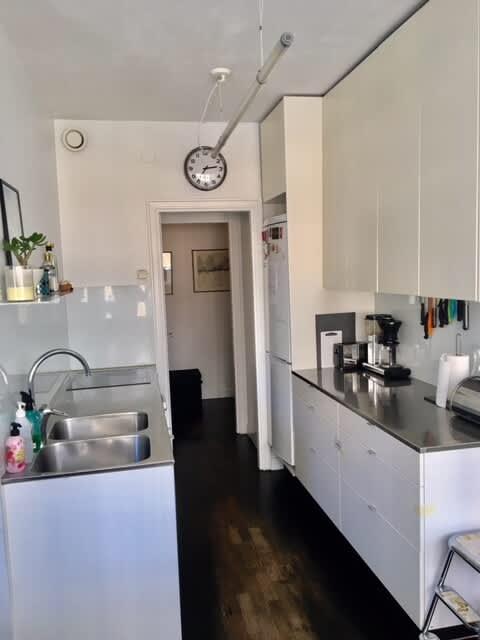 Ljust vardagsrum med soffa och konst i lägenhet på Södermalm; Stort sovrum med dubbelsäng på Södermalm; Enkelt sovrum på Södermalm; Ytterligare enkelt sovrum på Södermalm; Utrustat kök med spis och kyl på Södermalm; Privat terrass på lugn gata i Södermalm