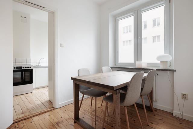 Ljust lägenhetsinteriör i Sundbyberg med minimalistisk inredning och grönskande omgivningar