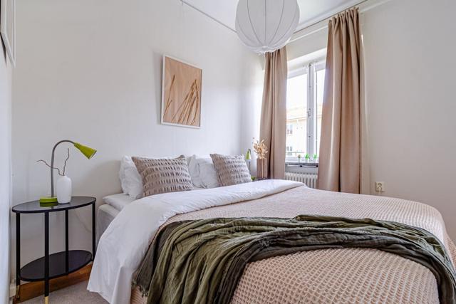 Living room with sofa bed and dining table in a cozy Globen apartment.