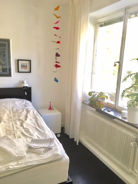 Ljust vardagsrum med soffa och konst i lägenhet på Södermalm; Stort sovrum med dubbelsäng på Södermalm; Enkelt sovrum på Södermalm; Ytterligare enkelt sovrum på Södermalm; Utrustat kök med spis och kyl på Södermalm; Privat terrass på lugn gata i Södermalm