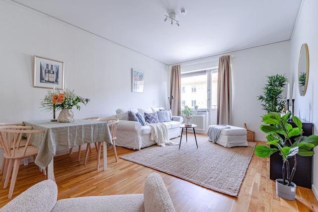 Living room with sofa bed and dining table in a cozy Globen apartment.