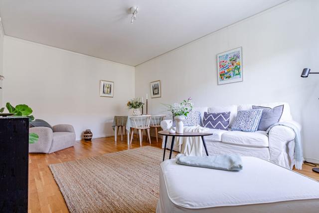 Living room with sofa bed and dining table in a cozy Globen apartment.